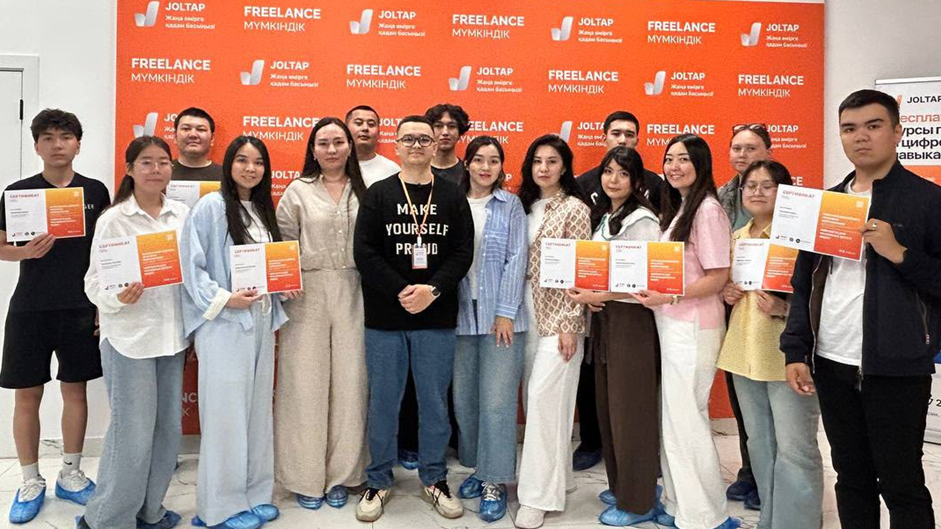 Молодые выпускники с сертификатами JOLTAP на фоне оранжевого баннера